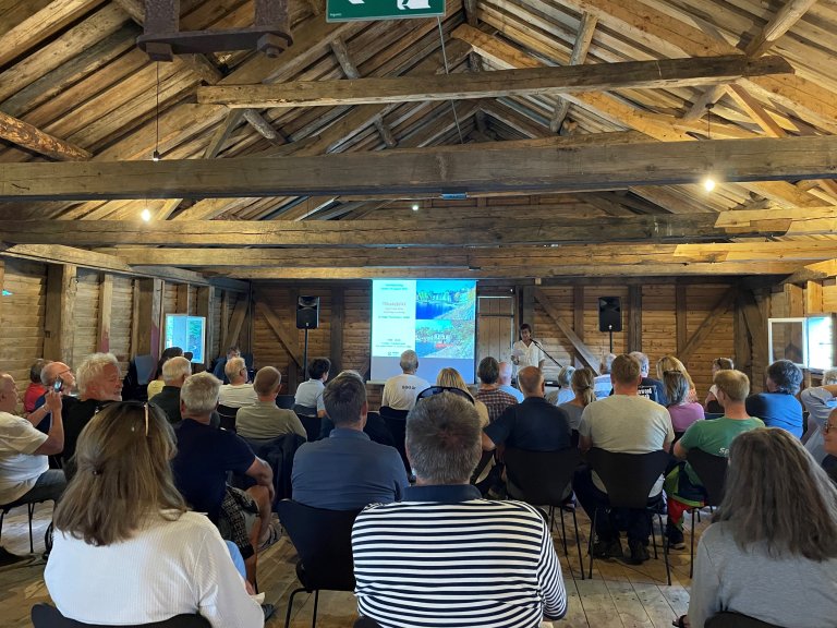 Forsamling vendt mot foredragsholder, bildeforedrag i den store låven. Furøya, Agde. Foto.